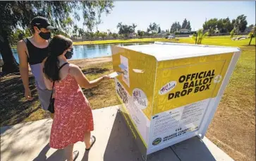  ?? Allen J. Schaben Los Angeles Times ?? CAITLIN HARJES of Orange, with Angel Santiago of Santa Ana, places her ballot in an official Orange County drop box. Secretary of State Alex Padilla said unauthoriz­ed GOP boxes have confused voters.
