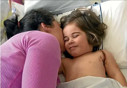  ??  ?? Olivia Kronfeld comforts her daughter Elle in her Starship hospital bed in the days following the crash that left her partner Christophe­r and their son Jack dead.