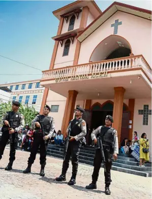  ??  ?? A real threat: Police standing guard outside a church in Bandar Acheh after the Surabaya bombings, but these terrorism attacks showed that new approaches to preventing and countering violent extremism in the region are needed. - AFP