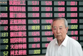  ?? PHOTO: AP ?? An investor walks past the stock price monitor at a private securities company in Shanghai on Tuesday. Investors are hoping that Guo Shuqing, who took over as head of China’s securities regulator seven months ago, will instil confidence in stock...