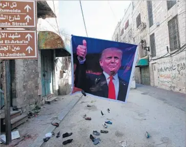  ?? Hazem Bader AFP/Getty Images ?? SHOES are thrown by Palestinia­n protesters at a poster of Donald Trump in the West Bank city of Hebron in February as a sign of disapprova­l of his support for Israel. Trump will visit two Mideast countries.