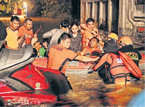  ??  ?? The Philippine coast guard, above, takes a family out of Cagayan de Oro city while a neighbour clings to a rescue dinghy, left