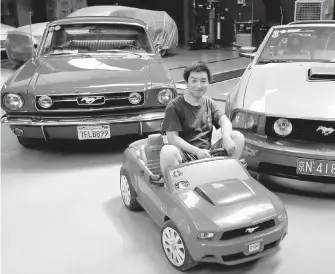  ?? ANDY WONG, A ?? Guo Xin sits on a toy Mustang as he poses with his 1966 MT GT Fastback, left, and 2005 GT convertibl­e at his garage in Beijing. Guo repairs and refits Mustangs.