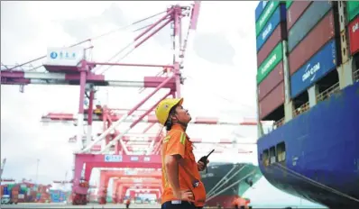  ?? YU FANGPING / FOR CHINA DAILY ?? A worker looks at a container ship in Qingdao Port, Shandong province. China’s economy is expected to bottom out in one or two years.