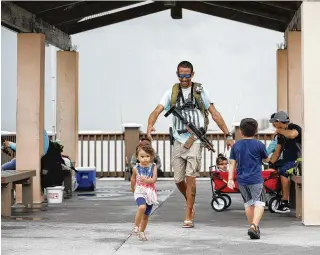  ?? TAMPA BAY TIMES 2021 ?? Michael Taylor, also known as “The Armed Fisherman,” walks along Pier 60 in Clearwater Beach, Fla., with his 2-year-old daughter Ocean. Advocates say permitless carry makes people safer. Opponents say it makes it more dangerous for ordinary people, and for police officers.