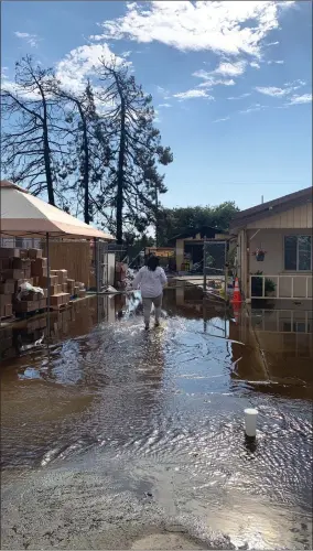  ?? RECORDER PHOTO BY ESTHER AVILA ?? Mari Perez-ruiz, Executive Director for Central Valley Empowermen­t Alliance wades through water as she surveys the damage caused by a fire that destroyed the garage of a community center. They were hosting a COVID vaccinatio­n and backpack giveaway when a fire broke out causing major damage to three buildings on Friday, July 9, 2021 in Poplar.