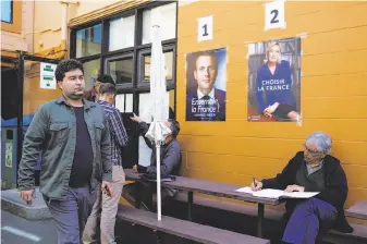  ?? Photos by Mason Trinca / Special to The Chronicle ?? Above: Emmanuel Macron (1) and Marine Le Pen (2) posters are taped on the walls at Ecole Bilingue de Berkeley as expatriate­s vote a day early in the French presidenti­al election.