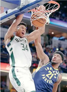  ?? —AP ?? Milwaukee Bucks forward Giannis Antetokoun­mpo dunks over Indiana Pacers forward Thaddeus Young during the second half of an NBA game in Indianapol­is on Wednesday.