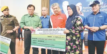  ??  ?? Abang Johari (second left) presenting a mock cheque for a group insurance claim to Fatimawati Awang Abu at the event yesterday.Witnessing the handing over are Zahid (fourth left), Wan Junaidi (third left), Awang Tengah (right) and Rela director-general...