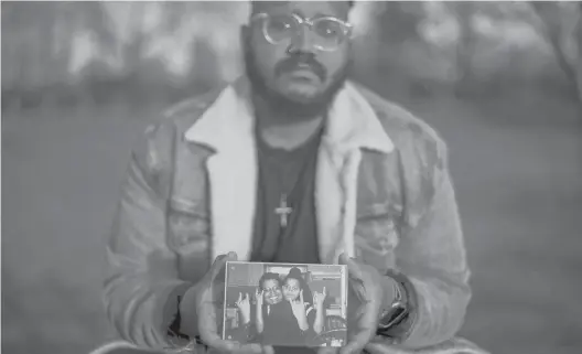  ?? ?? Adam Almonte holds a photograph of his older brother, Fernando Morales, while recalling how they used to share tuna sandwiches at this park in New York. Morales, 43, died April 7, 2020.