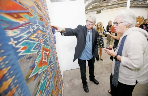  ??  ?? ABOVE: Irvin Trujillo of Chimayo speaks to Barbara Crowley of Manchester, Maine, in 2018 about his Best of Show piece at the Spanish Market preview at El Museo Cultural.