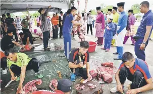  ??  ?? TINJAU: Zaki (kanan tengah) meninjau kerja-kerja melapah daging.