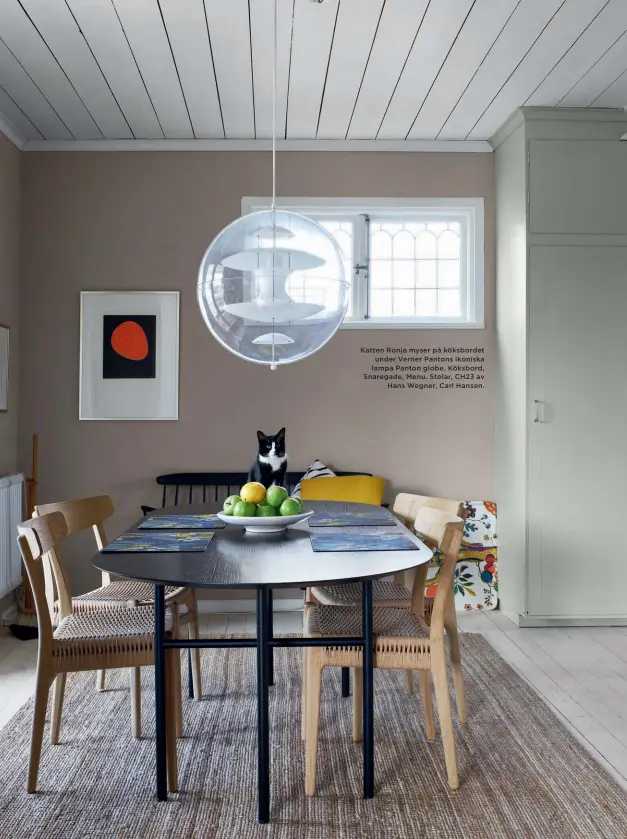  ??  ?? Katten Ronja myser på köksbordet under Verner Pantons ikoniska lampa Panton globe. Köksbord, Snaregade, Menu. Stolar, CH23 av Hans Wegner, Carl Hansen.