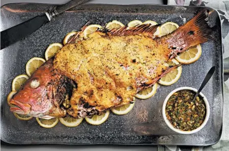  ?? ABEL URIBE/CHICAGO TRIBUNE PHOTOS; SHANNON KINSELLA/FOOD STYLING ?? The whole fish (snapper) is served with an herb sauce of garlic, parsley, lemon, orange and nuts. The lemon grass and garlic coating crisps on the grill.