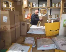  ?? Associated Press photo ?? Crow Smith puts a package away in a warehouse among shipping packages waiting to be picked up in Ogdensburg, N.Y.