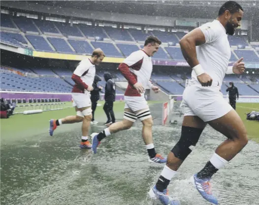  ??  ?? 0
England players make their way through puddles for the Captain’s Run at the Internatio­nal Stadium in Yokohama, where they will meet