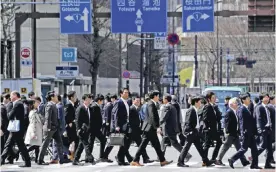  ??  ?? White-collar workers walk on a crosswalk in Tokyo yesterday. The Bank of Japan’s Tankan report a quarterly survey of more than 10,000 companies showed a reading of 12 among major manufactur­ers, rising from 10 in the previous survey. — AFP