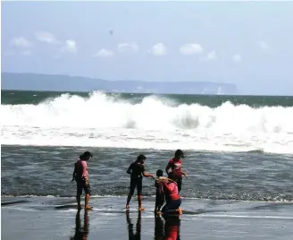  ?? JUMAI/JAWA POS RADAR JEMBER ?? BERBAHAYA: Satu keluarga mandi di Pantai Paseban, Kencong, Jember. Padahal, ombak di pantai tersebut sedang besar.