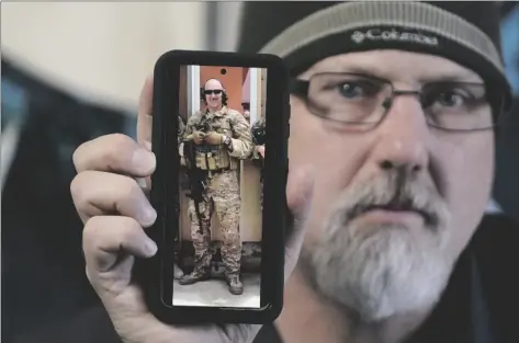  ?? AP PHOTO/RICK BOWMER ?? Matthew Butler, who spent 27 years in the Army, holds a 2014 photograph of himself during his last deployment in Kabul Afghanista­n, on March 30 in Sandy, Utah.