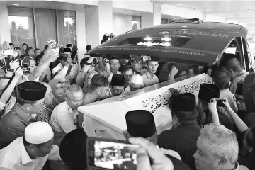  ??  ?? The coffin is carried into the hearse before leaving for his residence in Santubong.