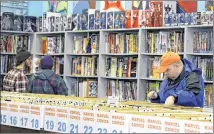  ??  ?? Robert Cramer (right) searches for comic books during New Comic Day at Carol & John’s Comic Book Shop, in Cleveland.