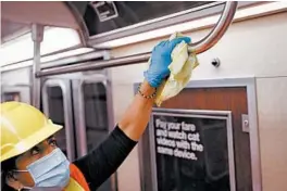  ?? JOHN MINCHILLO/AP ?? A contractor makes sure a handrail is clean in a subway car to control the spread of COVID-19 last summer in New York.