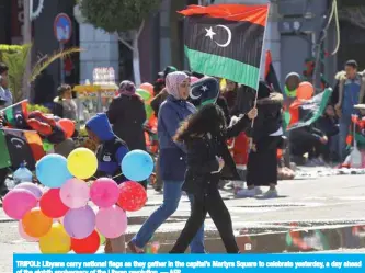  ??  ?? TRIPOLI: Libyans carry national flags as they gather in the capital’s Martyrs Square to celebrate yesterday, a day ahead of the eighth anniversar­y of the Libyan revolution. — AFP