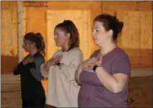  ??  ?? From left to right, Erin Katalenas, Marisa Sholl and Mindy Kern hold their hands to their chest and focus on breathing during a special female empowered yoga class.