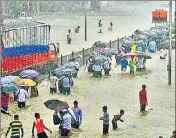  ?? AFP FILE ?? People wade through a flooded street during heavy rain showers in Mumbai, Maharashtr­a, in August this year.