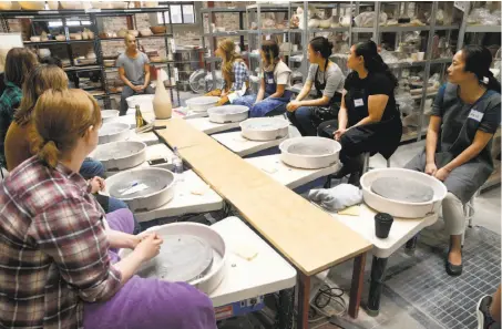  ?? Photos by Paul Chinn / The Chronicle ?? Students get tips on technique from master potter Eric Landon, visiting from Copenhagen for workshops at Clay by the Bay.