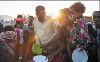  ?? NARIMAN EL-MOFTY — THE ASSOCIATED PRESS ?? Tigray refugees who fled the conflict in Ethiopia’s Tigray region, wait to get cooked rice served by Sudanese local volunteers at UmRakuba refugee camp in Qadarif, eastern Sudan, Monday. Tens of thousands of people have fled a conflict in Ethiopia for Sudan, sometimes so quickly they had to leave family behind. There is not enough to feed them in the remote area of southern Sudan that they rushed to.