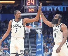  ?? PHELAN M. EBENHACK/AP ?? Nets forward Kevin Durant (7) and guard James Harden high-five after a basket during the first half against the Magic on Wednesday.