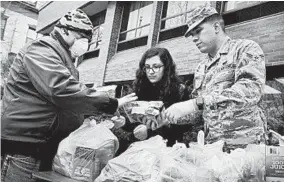  ?? SPENCER PLATT/GETTY ?? National Guard members hand out bags of food to residents near a containmen­t zone set up to halt the spread of coronaviru­s Thursday in New Rochelle, a suburb of New York City.