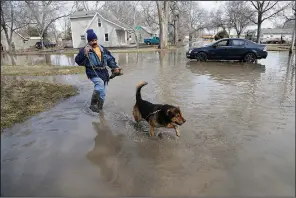  ?? AP/NATI HARNIK ?? Trino Nuno and his dog Tyson navigate flooded streets in Fremont, Neb., on Monday.