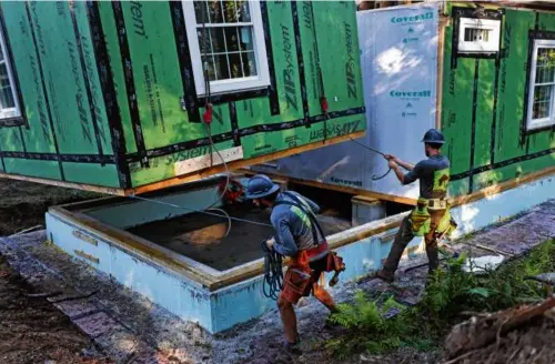  ?? DAVID L RYAN/GLOBE STAFF ?? A constructe­d accessory dwelling unit is lowered by crane into a backyard in Concord on Aug. 23, 2023.
