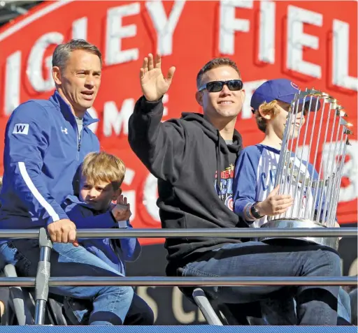  ?? DYLAN BUELL/GETTY IMAGES ?? President Theo Epstein (with GM Jed Hoyer, left) waves to the crowd from atop a bus during the Cubs’ World Series victory parade in 2016.