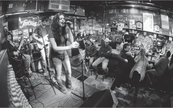  ?? PHOTOS: MARK HUMPHREY/ THE ASSOCIATED PRESS ?? Listening to a band in Tootsie’s Orchid Lounge in Nashville. Tourists and locals have a great selection of country artists to choose from, every night of the week.