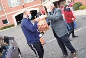  ?? Tyler Sizemore / Hearst Connecticu­t Media ?? Greenwich’s Antonio Silva, left, accepts a Thanksgivi­ng meal from Boys & Girls Club of Greenwich board member Bill Farrell during the Thanksgivi­ng meal distributi­on at the Boys & Girls Club in Greenwich on Tuesday.