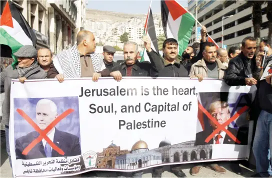  ??  ?? Palestinia­ns hold posters of the US President Donald Trump and Vice President Mike Pence during a demonstrat­ion in Nablus on Monday. (AP)