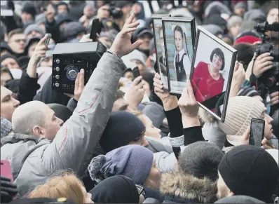 ??  ?? People hold portraits of relatives as they gather to pay last respects for the victims of a fire in Kemerovo.