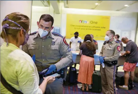  ?? JEREMY HOGAN/SOPA IMAGES/ZUMA PRESS/TNS ?? Police officers wear face masks as a preventive measure while verifying the identifica­tion of passengers arriving at an American Airlines flight in Texas on May 6 in Dallas.