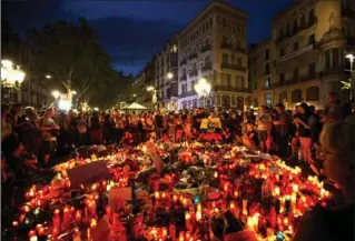  ?? EMILIO MORENATTI, THE ASSOCIATED PRESS ?? People gather at a memorial tribute to the victims on Barcelona’s historic Las Ramblas promenade on the Joan Miro mosaic, embedded in the pavement where the van stopped after killing at least 13 people in Barcelona, Spain.