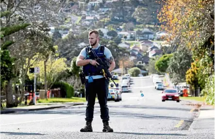  ?? — AFP ?? High alert: A police officer standing guard near the area where a shooting incident killed one officer and wounded another in a residentia­l neighbourh­ood in Auckland.