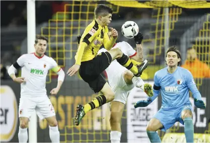  ??  ?? DORTMUND: Dortmund’s Christian Pulisic jumps for the ball in front of Augsburg goalkeeper Marwin Hitz during the German Bundesliga soccer match between Borussia Dortmund and FC Augsburg in Dortmund, Germany, Tuesday.