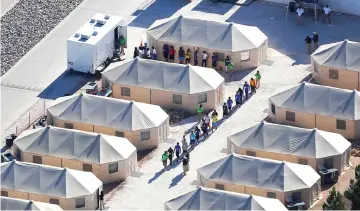  ??  ?? Immigrant children now housed in a tent encampment under the new ‘zero tolerance’ policy by the Trump administra­tion are shown walking in single file at the facility near the Mexican border in Tornillo, Texas.