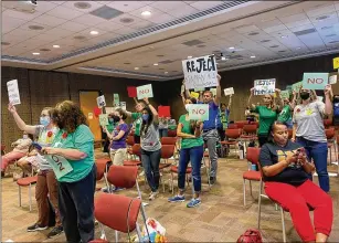  ?? VANESSA MCCRAY/VANESSA.MCCRAY@AJC.COM ?? Parents opposed to an Atlanta Public Schools recommenda­tion to rezone Midtown-area schools hold up signs during a Monday board meeting.