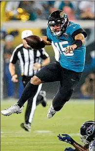  ?? AP/STEPHEN B. MORTON ?? Jacksonvil­le Jaguars quarterbac­k Gardner Minshew leaps over a Tennessee Titans defender during the Jaguars’ victory Thursday night. Minshew passed for 204 yards and two touchdowns.