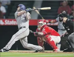  ?? Stephen Dunn Getty Images ?? MIKE NAPOLI of the Rangers hits a home run in the second inning as Angels catcher Martin Maldonado and umpire Stu Scheurwate­r look on.