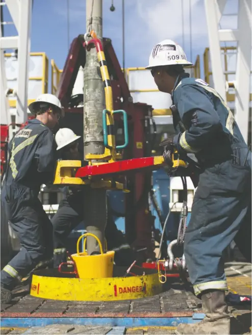  ?? Brent Lewin / Bloombe
rg files ?? Oil riggers torque a pipe at an oil production facility owned by Canada-headquarte­red Cenovus Energy Inc.
and U. S.-headquarte­red Conocophil­lips.