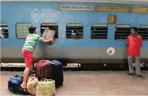  ?? AFP ?? Change on the horizon A passenger offloads luggage through the emergency window of a Karnavati Express coach in Mumbai. India’s first bullet train is set to slash journey times between Ahmedabad and Mumbai.